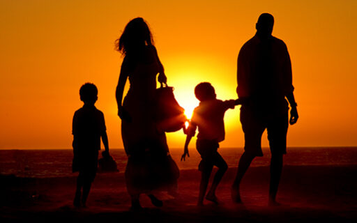 Mother and father stroll on Los Angeles beach with their children